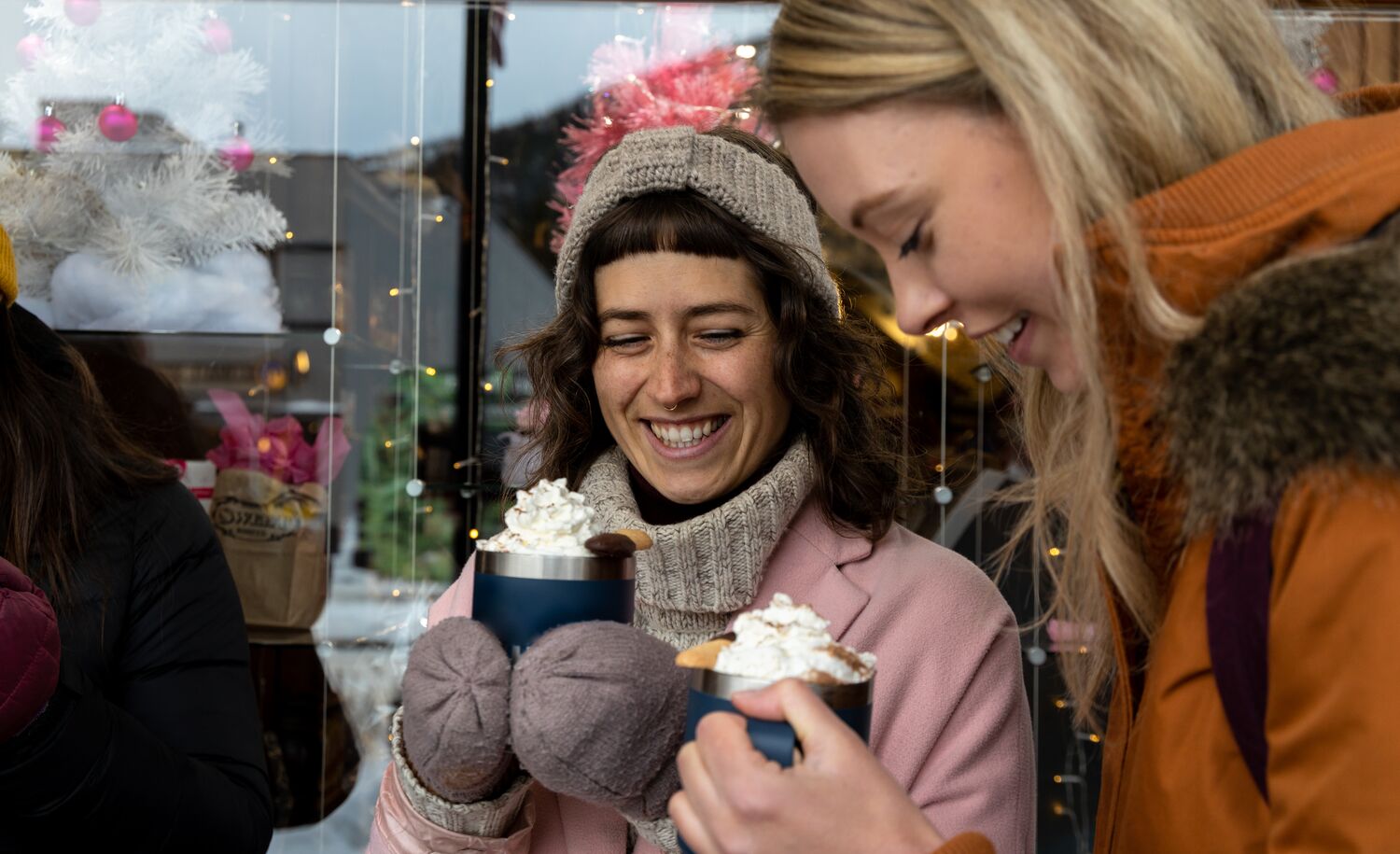 Two girls enjoy a hot chocolate on Banff Ave in Banff National Park.